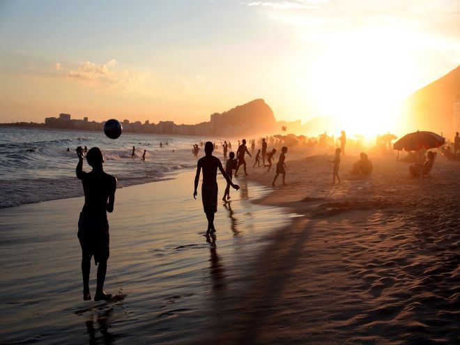 Praia de Copacabana com banhistas e pessoas jogando bola