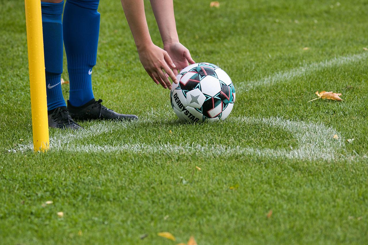 jogador de futebol ajeitando a bola no campo para cobrar escanteio 