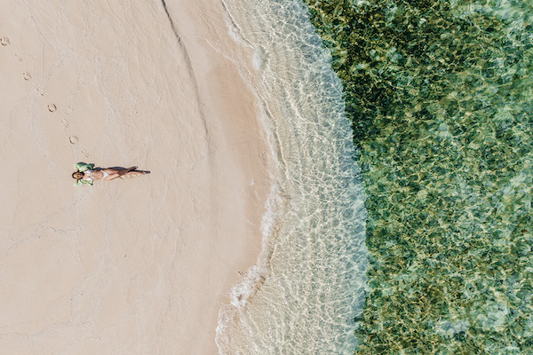 aerial view of Brooke Blurton lying on the sand by the waters-edge